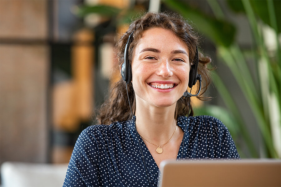Woman at her desk smiling and wearing a headset