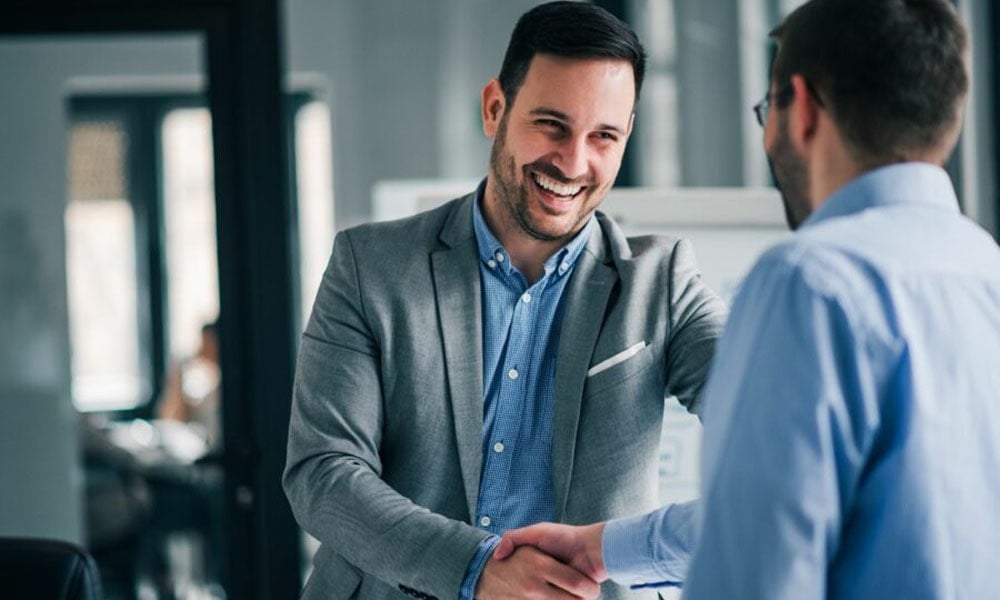 Two colleagues shaking hands and smiling