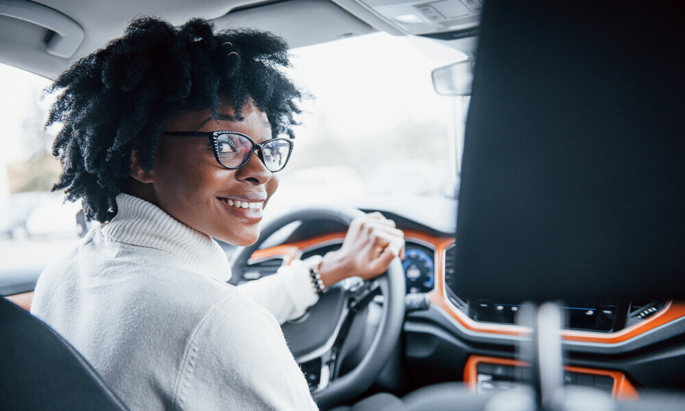 Woman in car sitting on drivers side looking back at camera