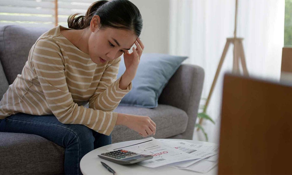 Woman sat down with a calculator looking at bills