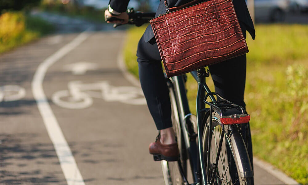 riding bike on bike path brown messenger bag